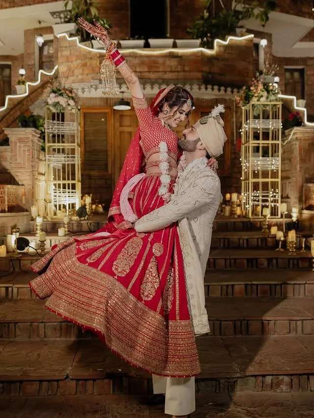 Indian couple wedding pose highlighting bride’s lehenga and groom’s sherwani