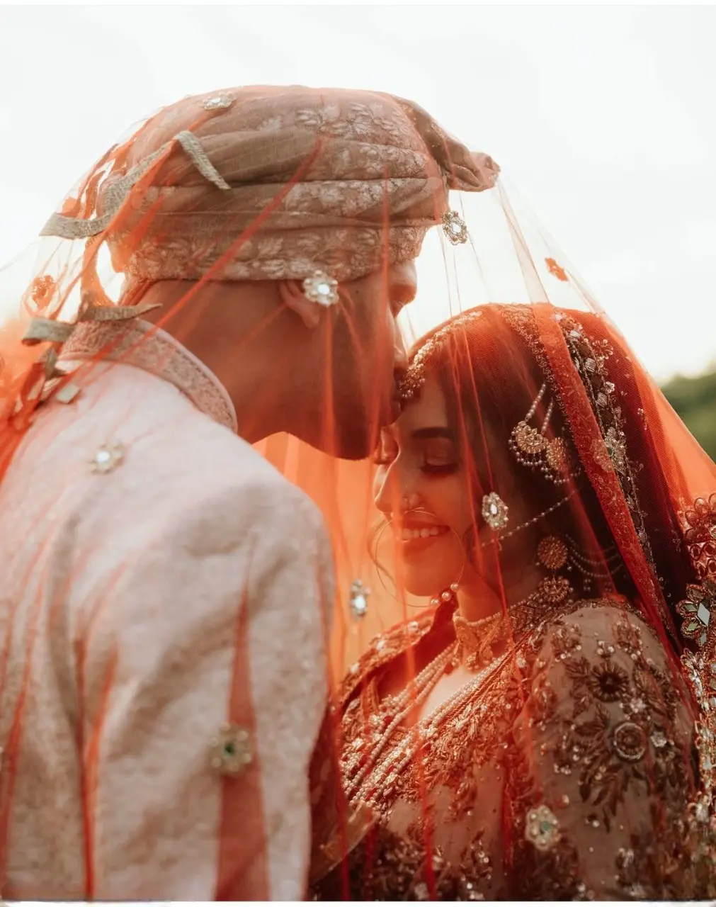 Indian bride and groom wedding pose with soft sunlight creating a dreamy halo effect